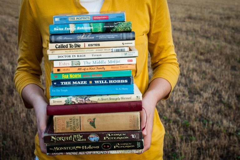 Person holding a tall stack of books